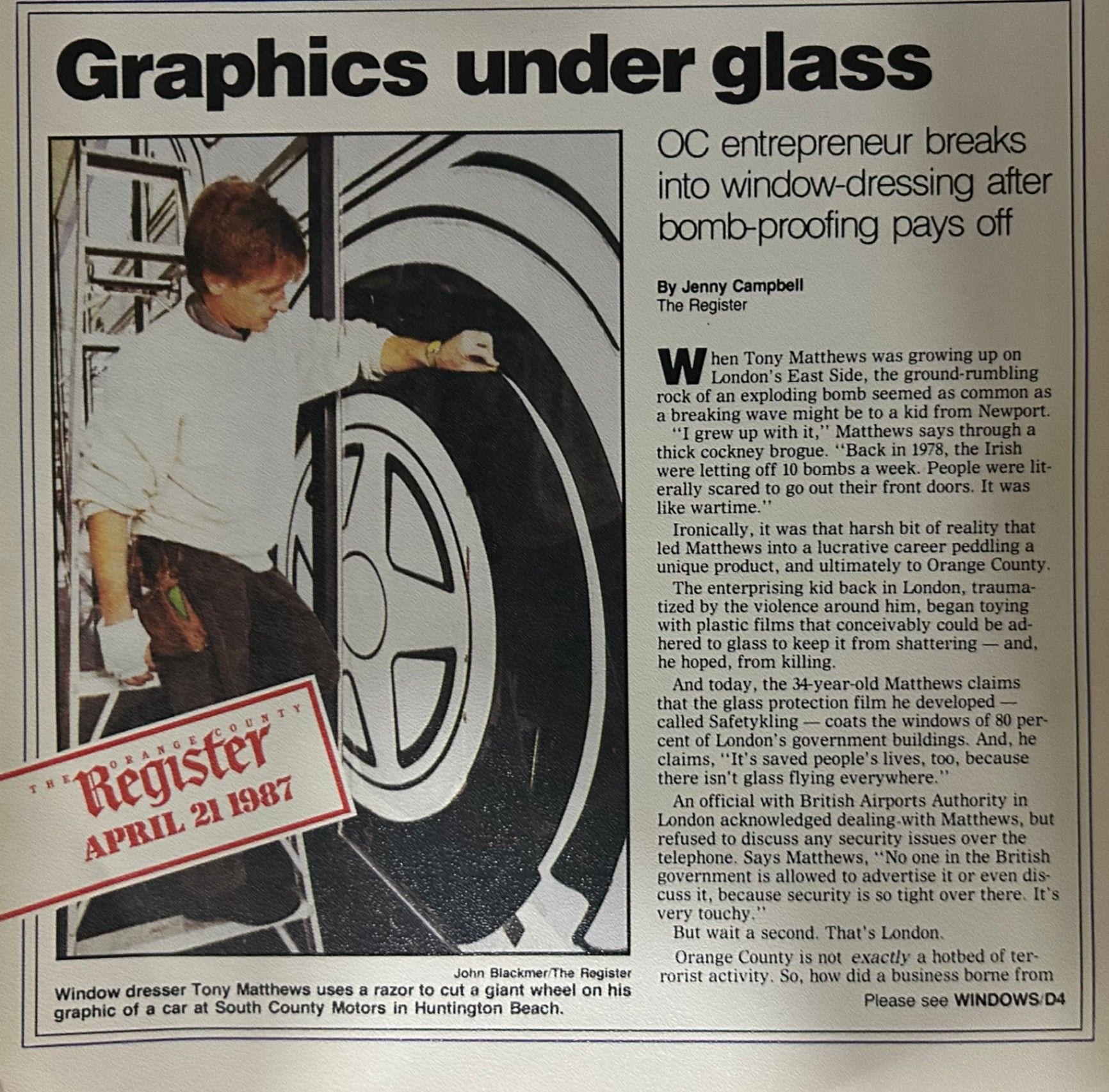 Orange County Register page from April 21, 1987, headlined Graphics under glass, showing Tony Matthews working on a giant car-wheel window graphic